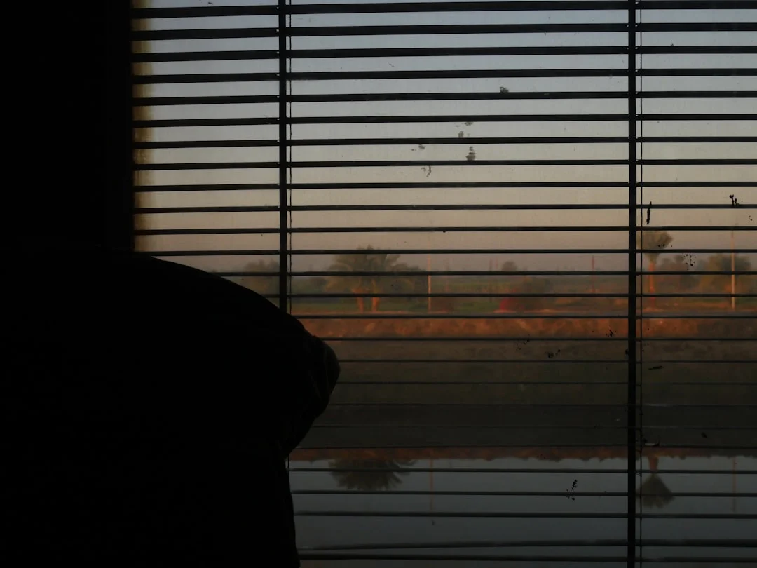 A person sitting peacefully by a window with warm morning light, reflecting quietly