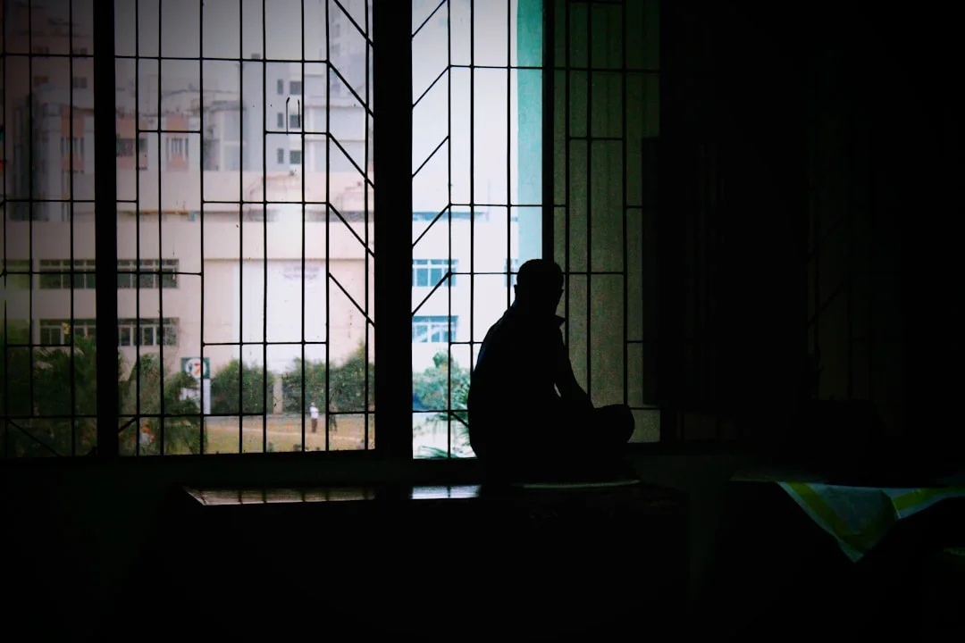 A person sitting by a window in soft light, paused in thought, practising emotional awareness