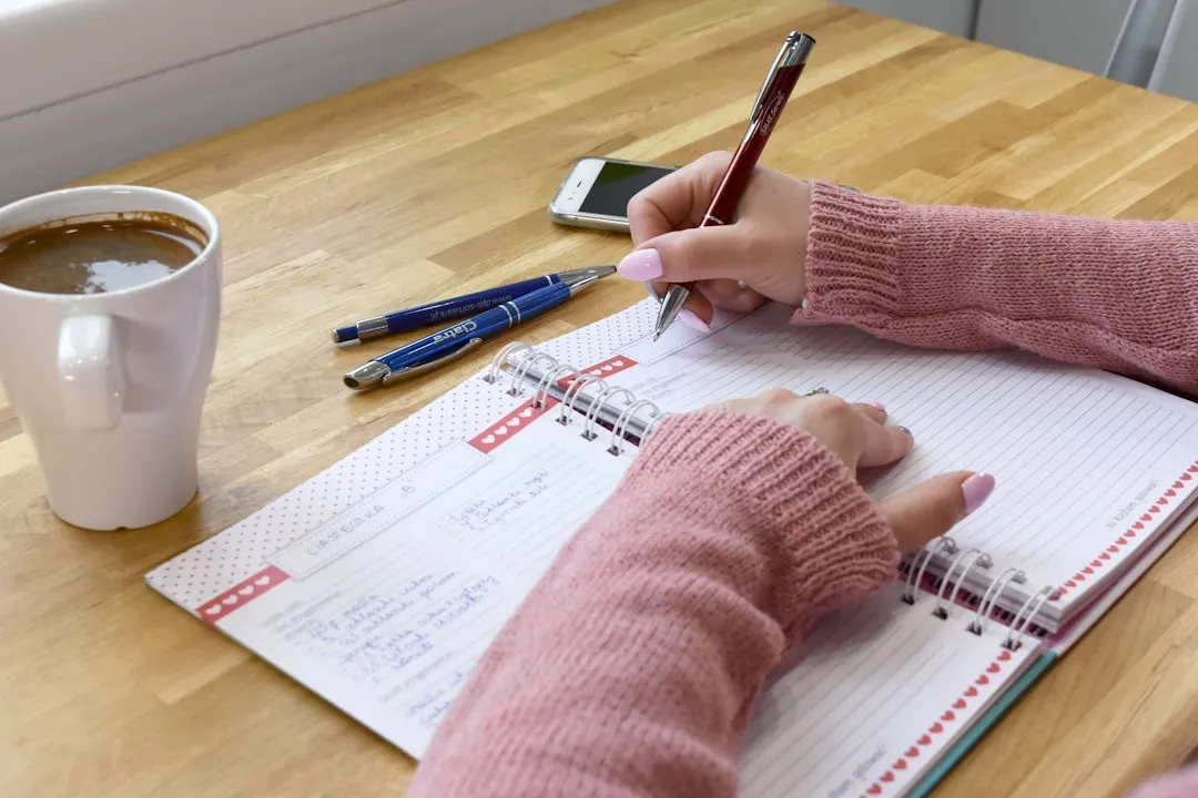 Person writing in a journal with a cup of tea, practising mood journaling